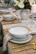 Elegant table setting with decorative bowls, plates, and gold cutlery on a patterned tablecloth.