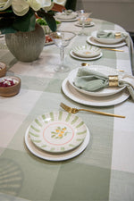Elegant table setting with plates, glasses, and cutlery on a checkered tablecloth.