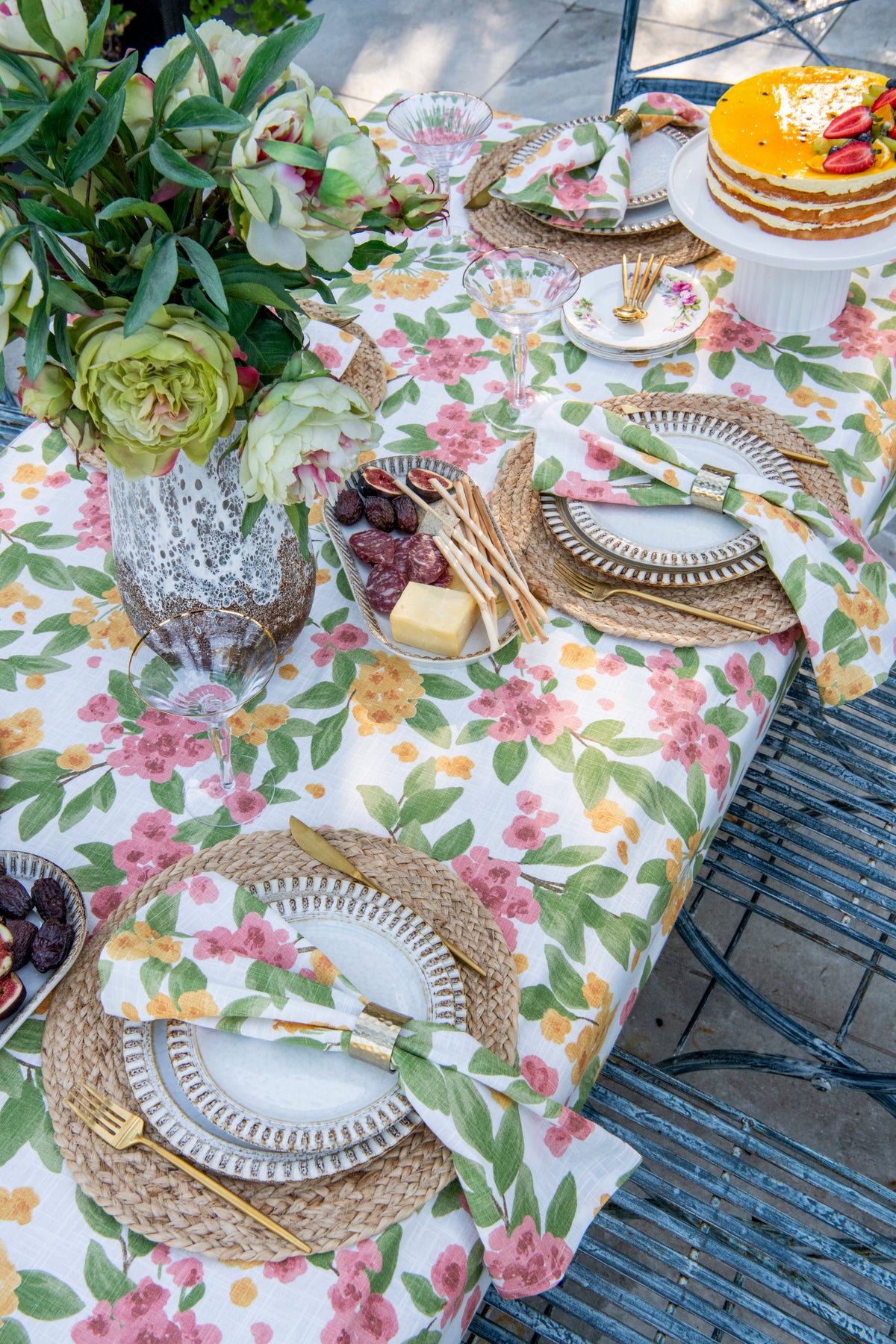 Floral Reverie pink and orange floral cotton tablecloth featuring colourful flowers and botanical foliage on an off-white background. Copy
