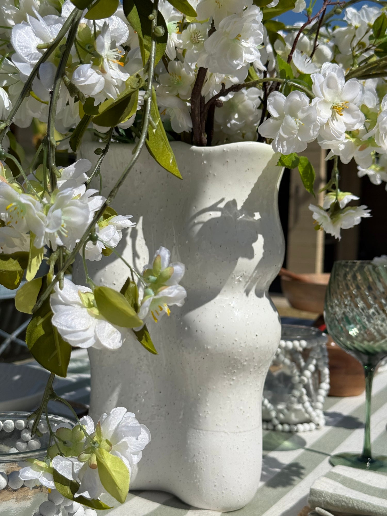 Sierra cream ceramic vase with a sculptural wavy silhouette, half-dipped glaze and raised multicoloured speckled detailing.