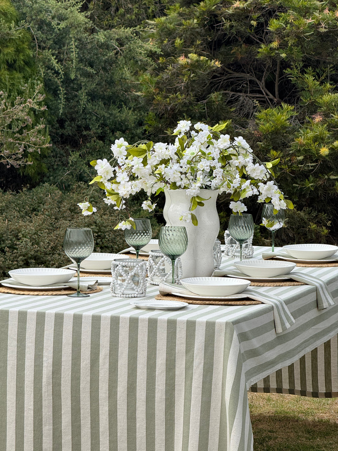 Olive Stone Stripe green and off-white cotton tablecloth with a classic striped pattern, styled on a rectangular dining table.