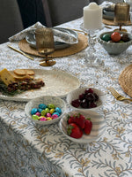 Dining table set with plates, bowls of fruit, and decorative items on a patterned tablecloth.