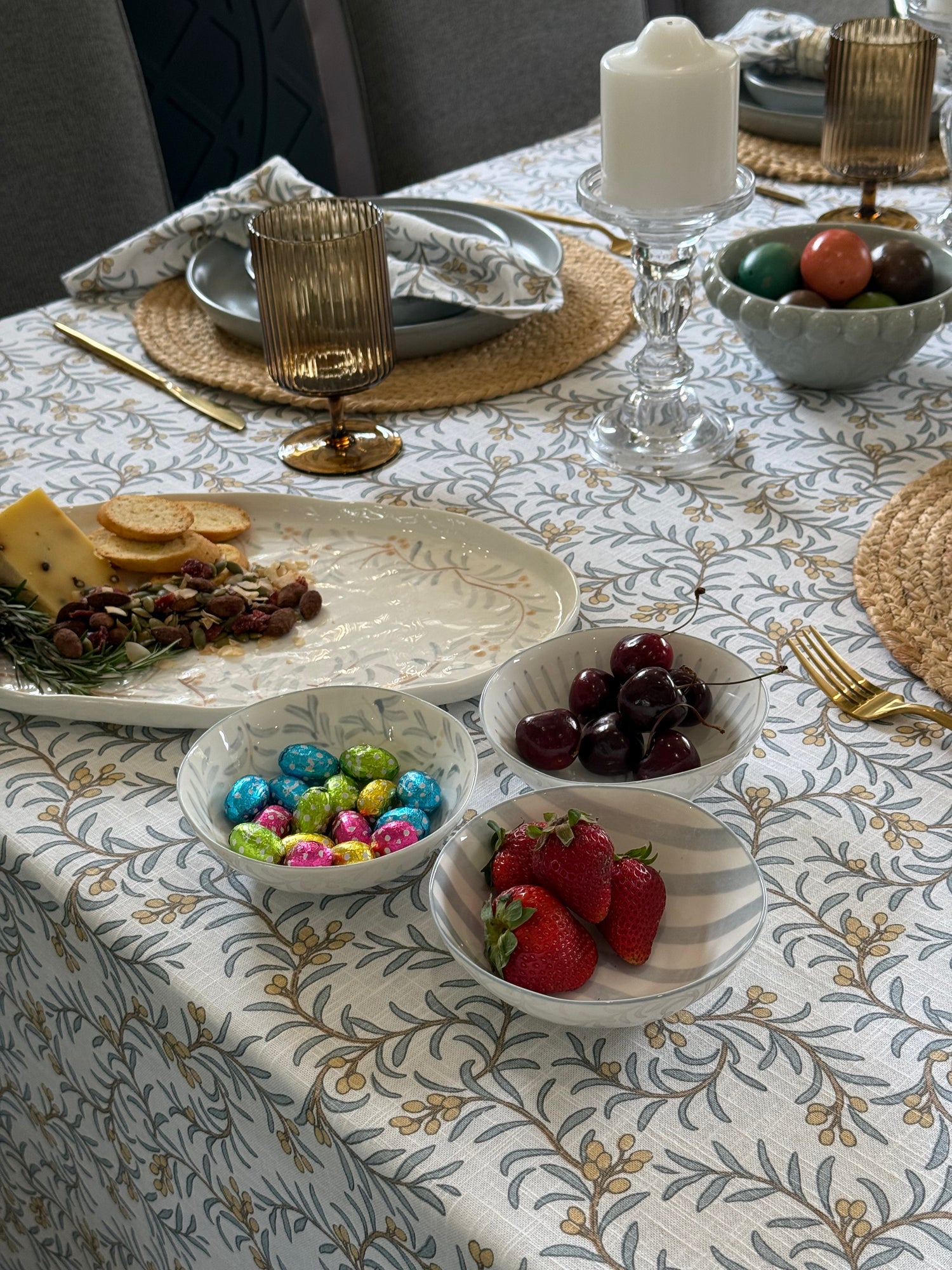 Dining table set with plates, bowls of fruit, and decorative items on a patterned tablecloth.