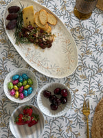 Assorted snacks including cheese, crackers, and fruits on a patterned tablecloth.