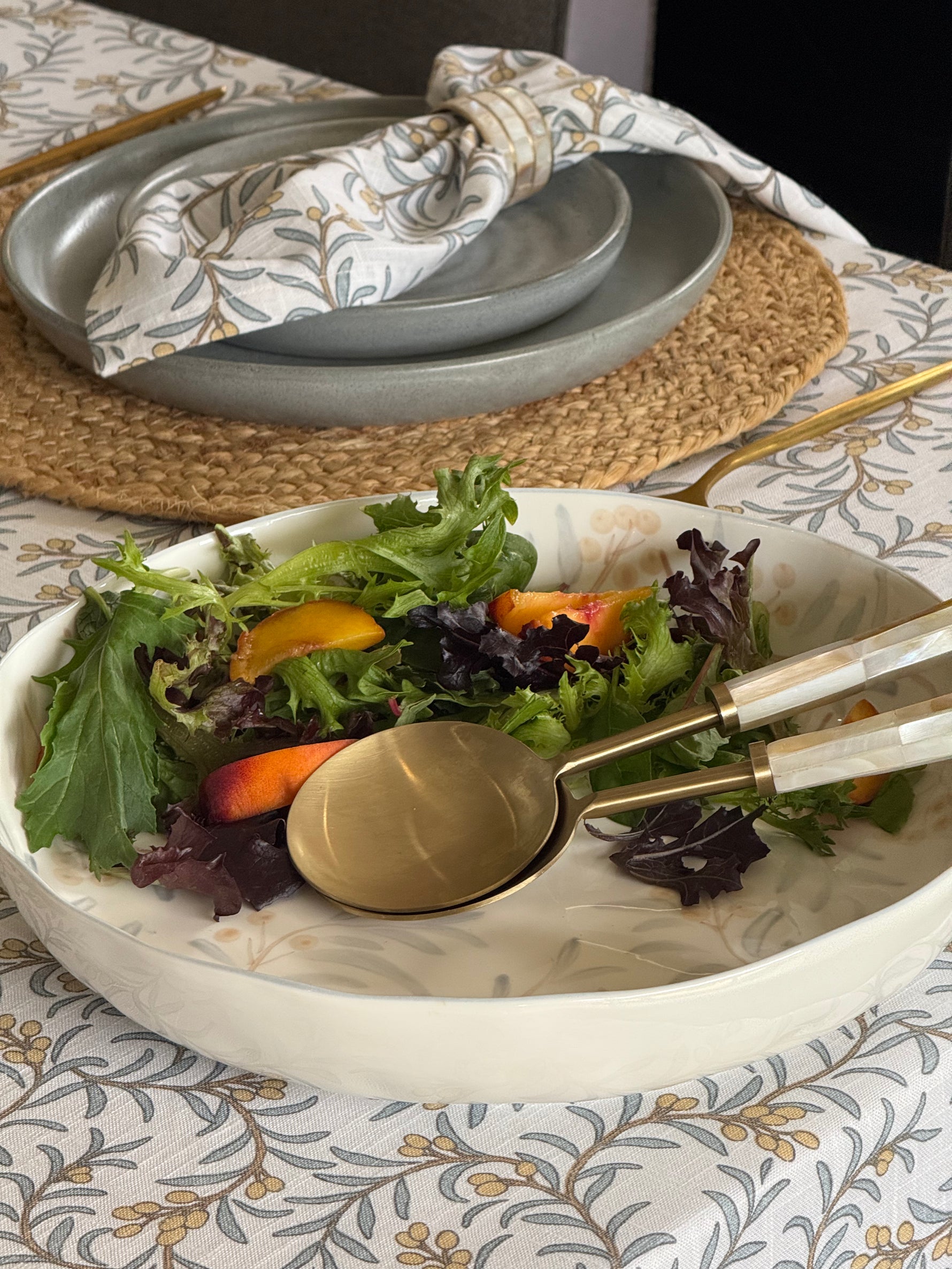 Large hand-painted ceramic serving bowl with blue-grey and apricot botanical motifs on a cream background.