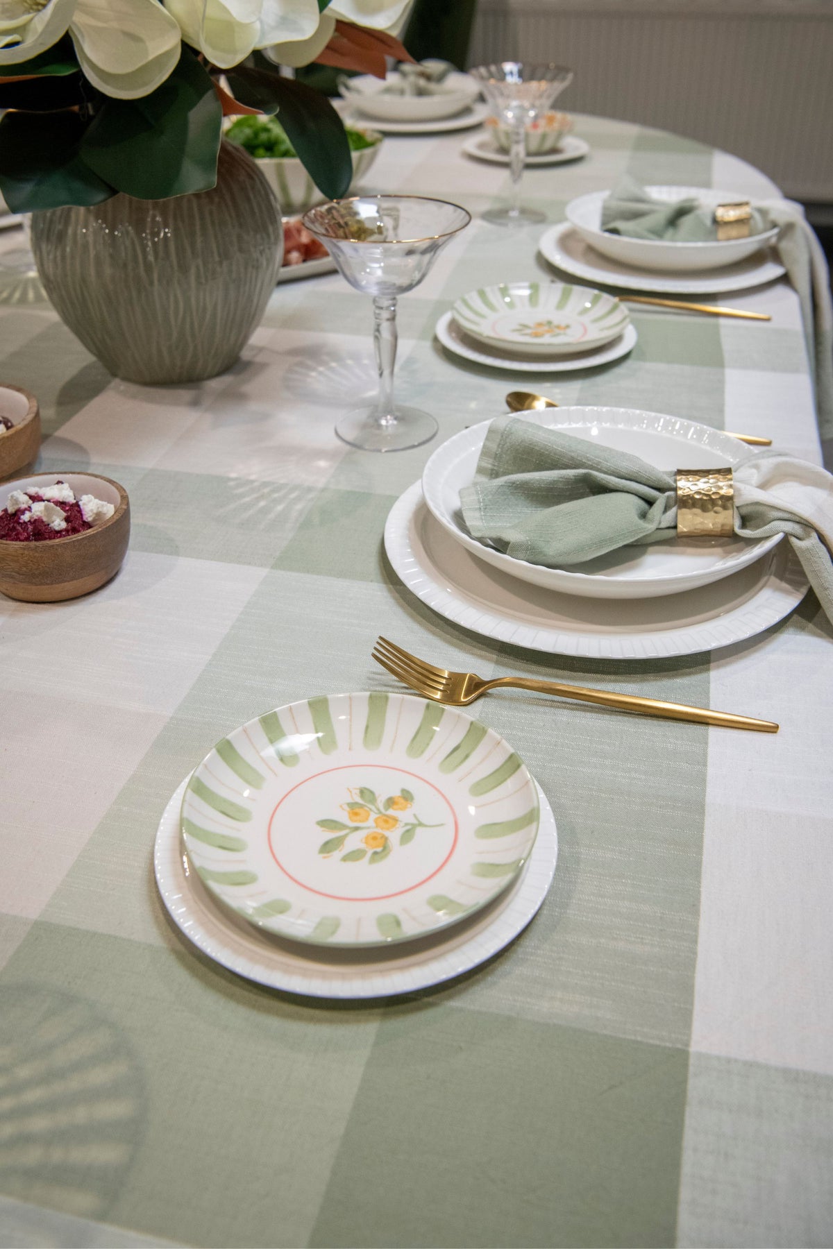 Elegant table setting with plates, glasses, and cutlery on a checkered tablecloth.