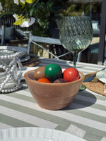 Wooden bowl with colorful balls on a striped tablecloth outdoors