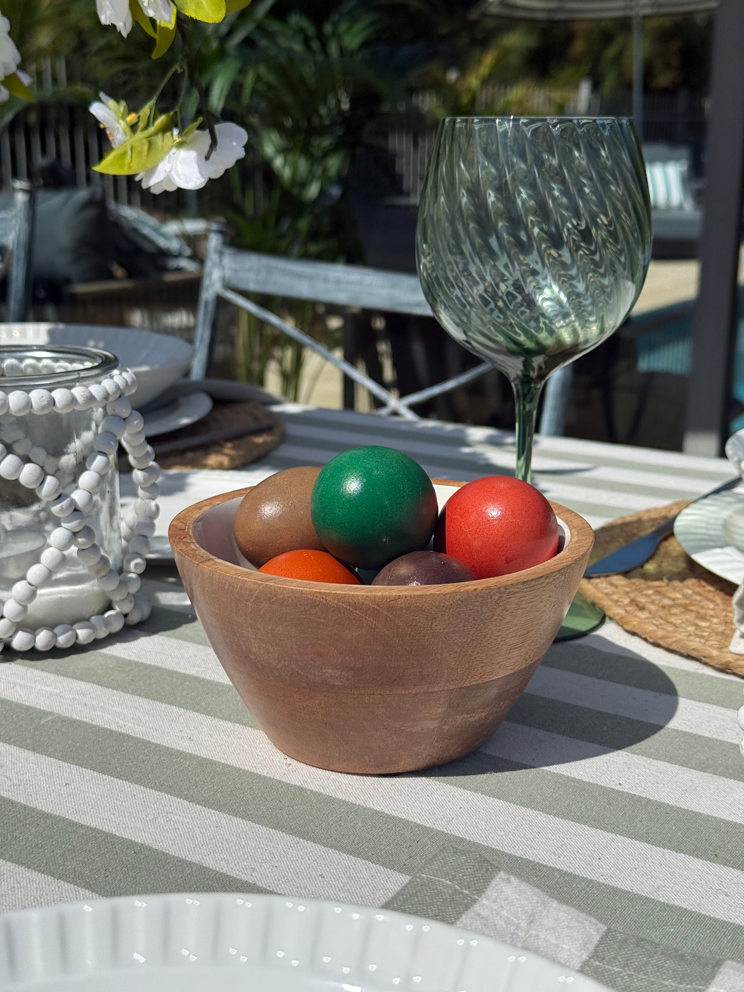 Wooden bowl with colorful balls on a striped tablecloth outdoors