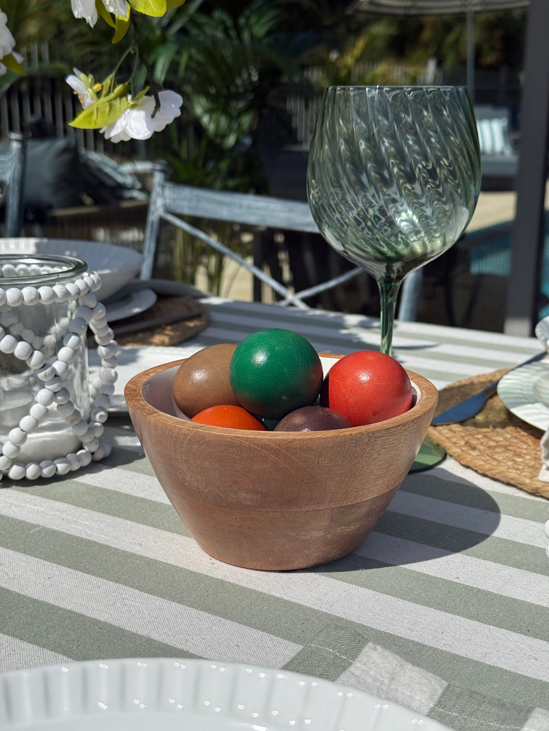 Wooden bowl with colorful balls on a striped tablecloth outdoors