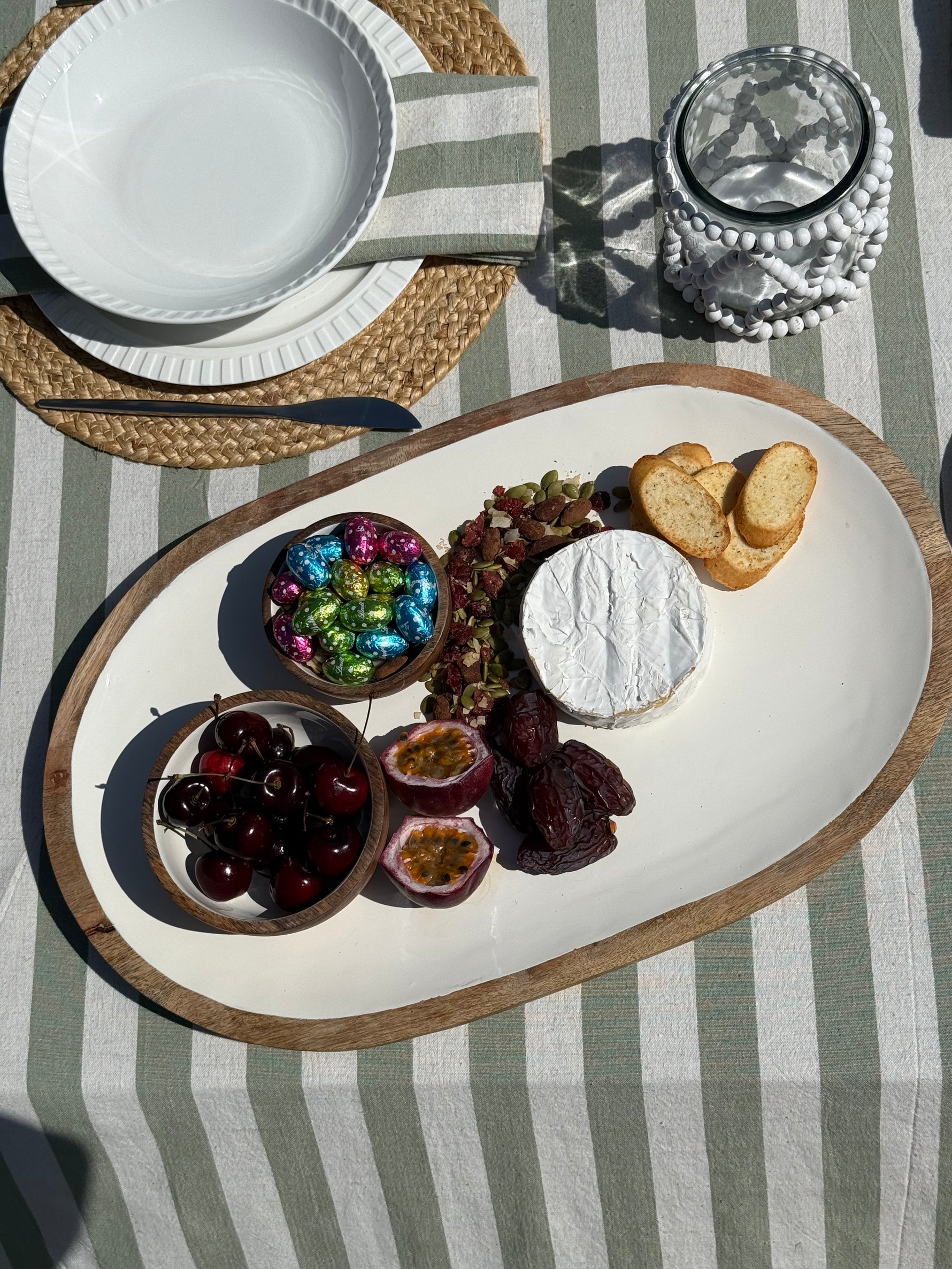 Platter with cheese, fruits, and crackers on a striped tablecloth
