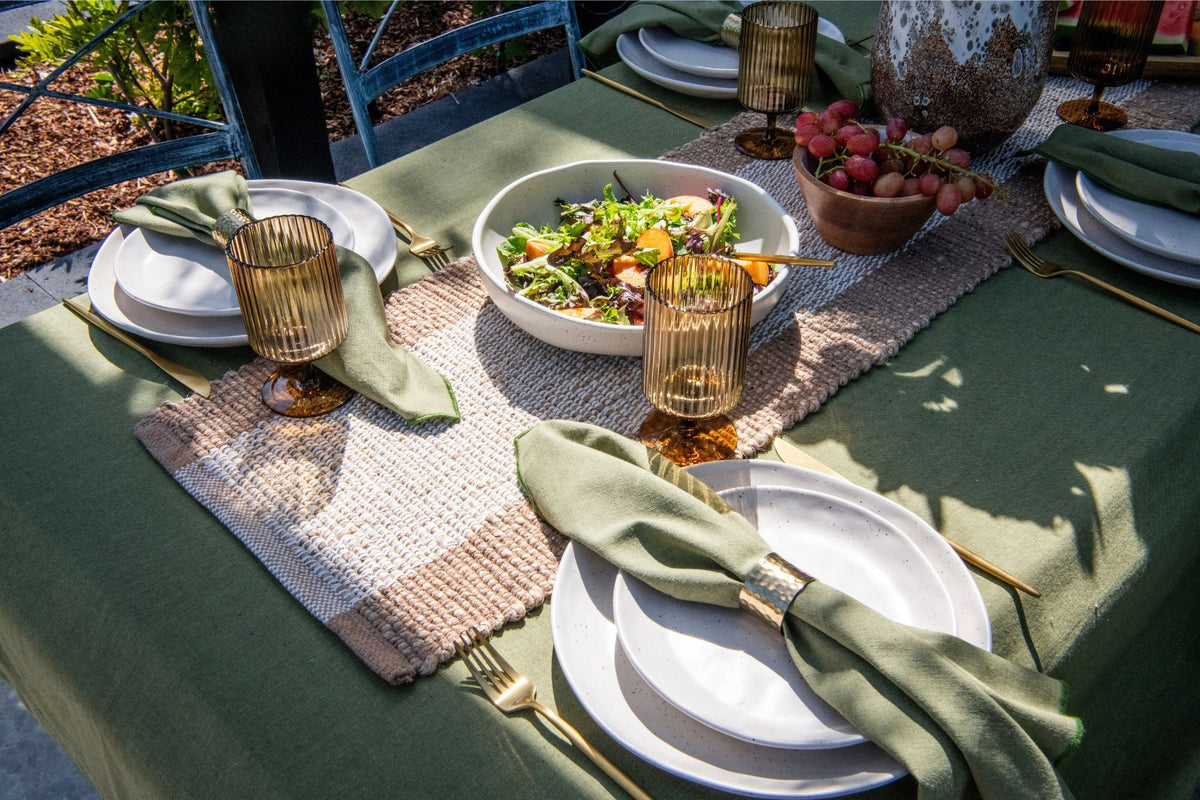 Set of four sage green cotton table napkins with contrasting dark green embroidered edging.