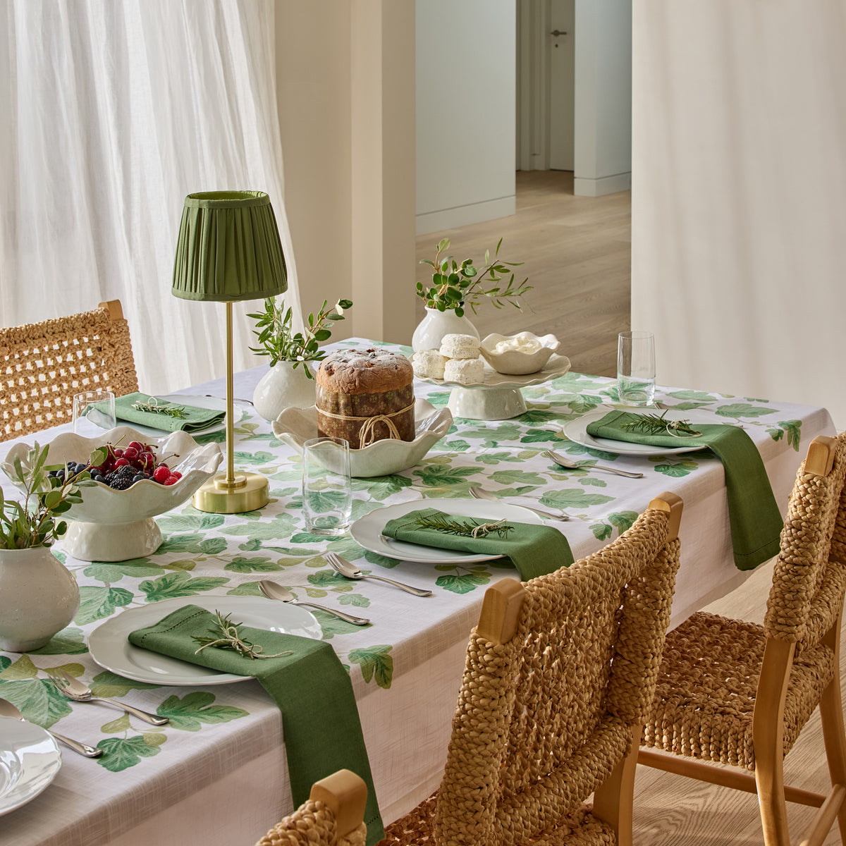 Fig & Vine green botanical tablecloth featuring trailing fig leaves and young green figs on a crisp white background.
